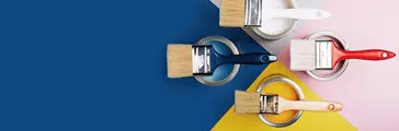 Clean paint brushes laying on top of open paint cans